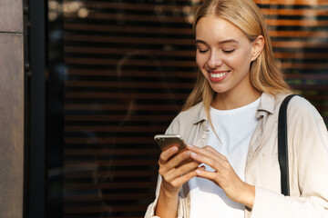 Happy woman using smartphone outdoors