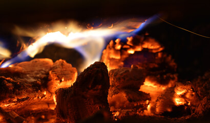 Feuer im Kamin mit brennendem Holz, Flammen und Glut, schwarz, orange, blaue Flamme