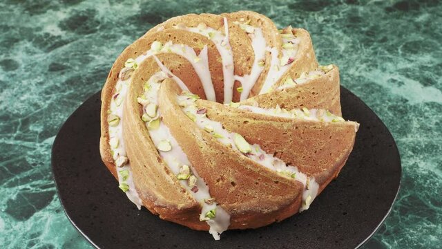 Homemade pumpkin bundt cake drizzled with an orange glaze and sprinkled with chopped pistachios, seamless rotation