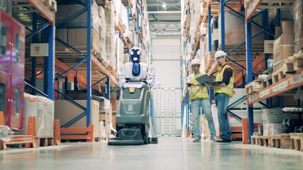 Male workers are managing a human-like robot with a cleaner