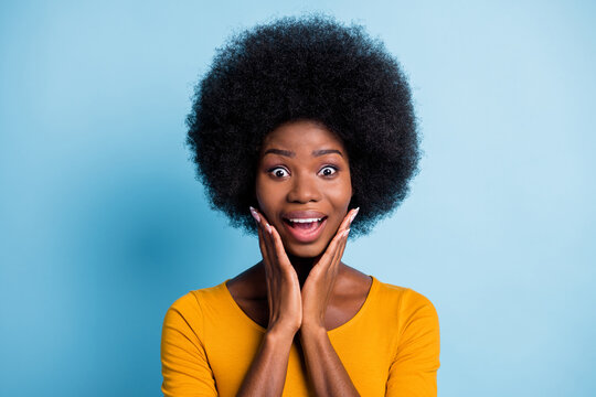 Photo Of Cute Black Girl Volume Hairstyle Open Mouth Arms Cheeks Crazy Face Wear Yellow Shirt Isolated Blue Color Background