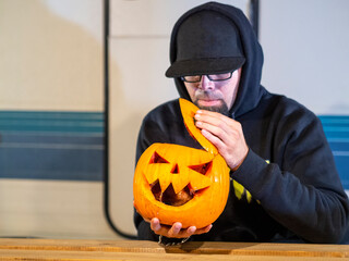 Hombre joven con gorra abriendo una calabaza de halloween