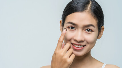 Close-up young Asian woman wearing contact lens, macro shot.