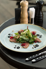 green salad with pine nuts, meat and raspberry on the table at restaurant