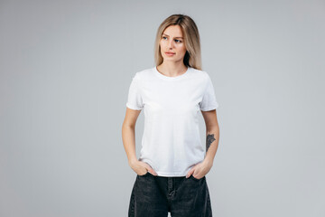 Stylish blonde girl wearing white t-shirt posing in studio