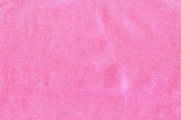 The texture of natural cotton fabric is pink. The background is a simple fabric, not very smooth, crumpled.