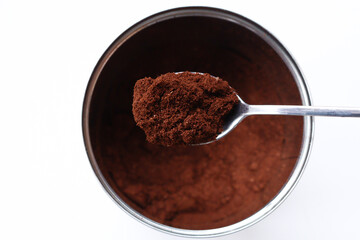 Instant coffee in a metal jar and in a spoon close-up on a white background. The view from top