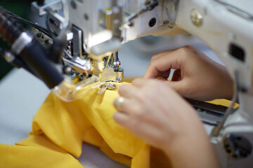 A woman is sewing with a Lok Mak machine in a fabric factory. 