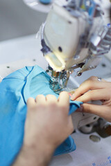 The worker is sewing a textile with a sewing machine in a fabric factory.