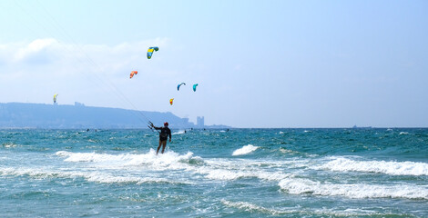 Sunny summer beach with people engaged in kitesurfing. Israel. Kiryat Yam. Haifa