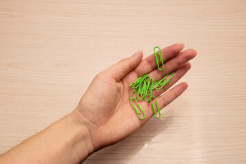 Left female hand holds green paper clips