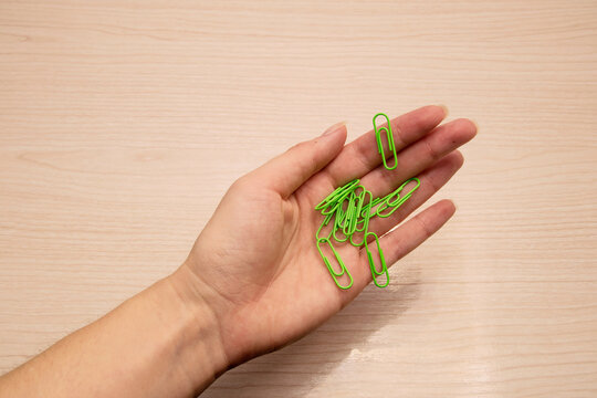 Left Female Hand Holds Green Paper Clips