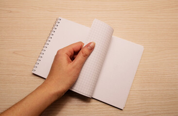 Obraz premium Left female hand flips through white notebook