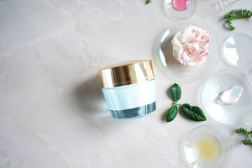 jar of face cream on a light background with medical glasses and different herbal ingredients. The concept of natural ingredients in cosmetics