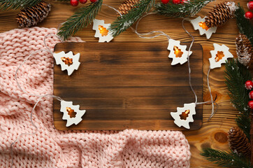 Christmas or new year wooden background among spruce branches, curly lights in the shape of Christmas trees.