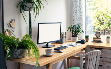 Vintage office desk with monitor with empty screen in vintage office room. Modern workspace with green plants, window and wooden table and decor. Home office.