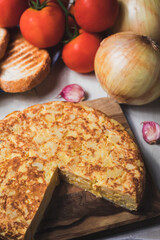 Tortilla de patatas encima de una tabla rústica marrón claro