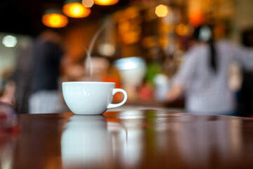 Hot Coffee Cup on Wood Table in blurred Coffee Shop background.