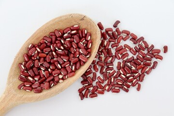 Azuki Beans in a wooden spoon on white background. Red beans. Raw food.