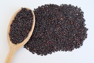 Black rice in a wooden spoon on white background. Raw rice.