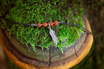 Metal feather pendant with rudraksha seed beads bracelet on mossy polypore