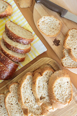 Top view homemade breads on yellow napkin wooden table in kitchen. Wooden chopping board and knife on the table. Homemade food concept.