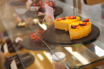 Delicious mango raw cake on display at confectionery store, copy space