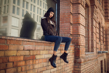 Outdoor lifestyle portrait of pretty young girl, wearing hipster swag grunge style on urban background. Wearing hat and jeans denim. Spring fashion woman. Toned style instagram filters.