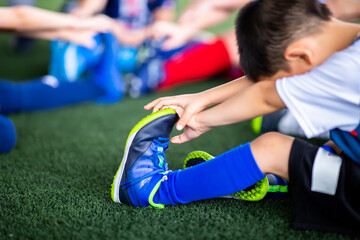 Selective focus to Kid soccer players are stretching their hands to catch their feet to warming up...