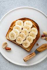 peanut butter banana sandwich in a white plate on gray background, top view