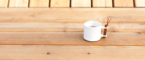 Modern coffee cup with steam on wood. Moderne Kaffeetasse mit heißem Kaffee auf Holz.