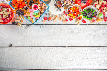 Fototapeta premium Set of Halloween sweets and candies. Various kids treats for Halloween - candy, cereal breakfast, sweets, with school lunchbox and bucket, flatlay copy space top view