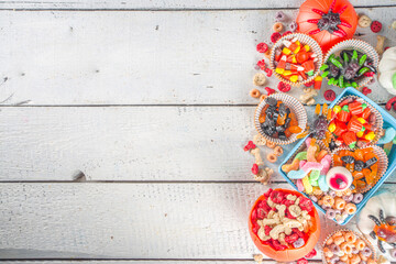 Set of Halloween sweets and candies. Various kids treats for Halloween - candy, cereal breakfast, sweets, with school lunchbox and bucket, flatlay copy space top view