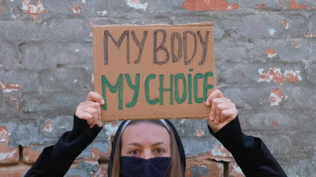 Young woman protester holds cardboard with MY BODY MY CHOICE sign. Girl protesting against anti-abortion laws. Feminist women power march.Feminism concept equal opportunity rights independence freedom