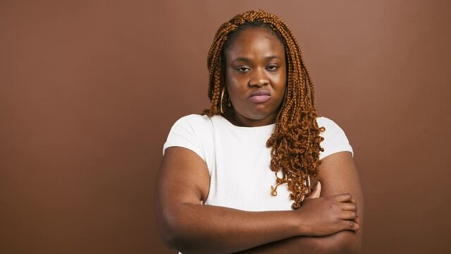 Offended african american woman standing with crossed arms, shaking head as rejection, brown background