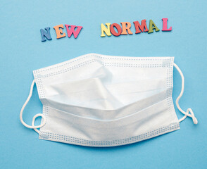disposable medical face mask and lettering new normal on blue background