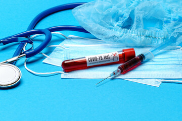 Medical lab concept - Covid-19 blood sample in test tube and syringe on blue background