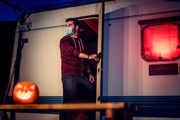 Chico joven on mascarilla en caravana con ambiente de halloween