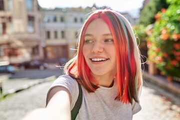 Teenager girl with trendy hairstyle, young fashion art blogger records stream in city