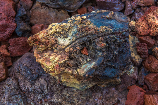 A multicolored volcanic rock enb with a bathing plan lies on dried lava
