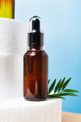 Dark Glass Bottle with Pipette Essential Oil, Serum on Blue Background. Face, Skin care Beauty closeup on podium.