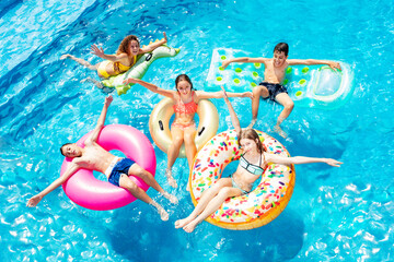 Many happy children friends swim on inflatable ring toys view from above