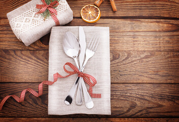 Gift box is festively decorated with Christmas branch and on wooden desk. Top view selective focus.