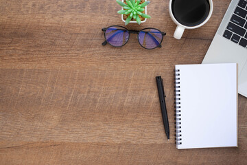 Top view above of Wooden office desk table with keyboard, notebook and coffee cup with equipment other office supplies. Business and finance concept. Workplace, Flat lay with blank copy space.