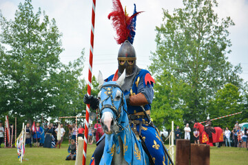 A rider in armor with a spear on a horse. The action takes place at a medieval festival.