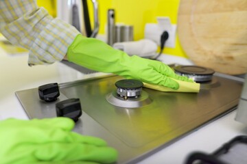 Close-up of woman's hand washing hob of gas stove