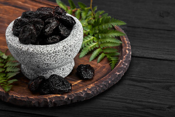 Fresh prunes in stone bowl. Prunes on stone dark table. Prunes healthy food. Dried plums in bowl.