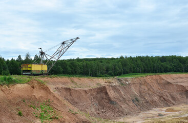 Fototapeta premium Largest Walking Dragline excavator working in dolomite open-pit. Full-revolving electric digging walking machine with dragline working equipment. View on industrial landscape in mining quarry