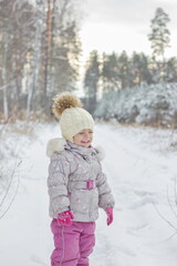 Portrait of little girl is snowy forest in winter.
