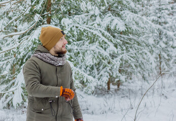 Fototapeta na wymiar Young bearded man walking in snowy forest in winter.